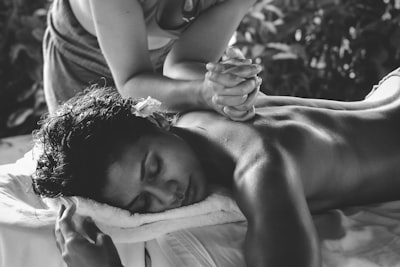 Woman is lying on the massage table with her head reasting on the white towel