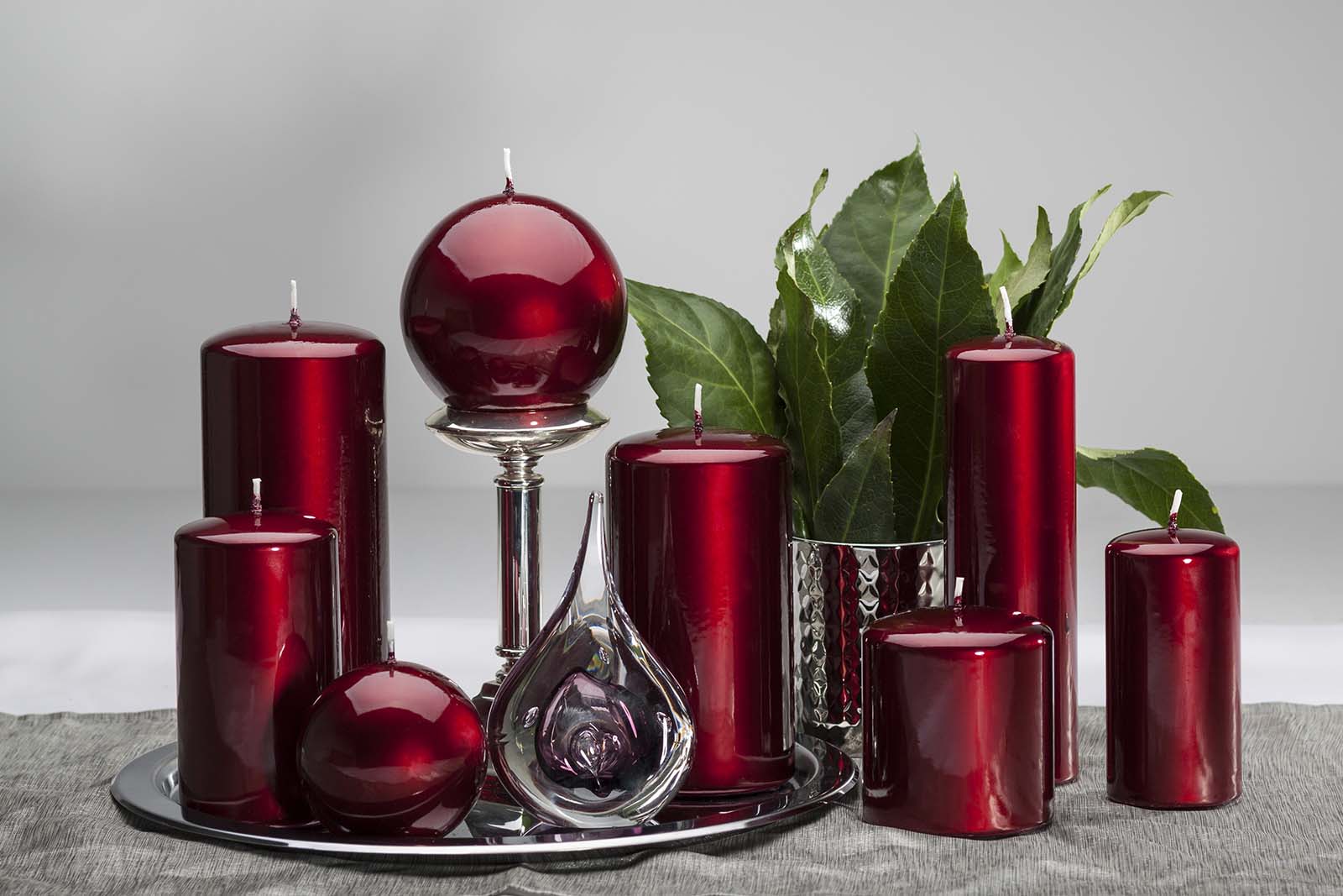 Pillar and round burgundy candles displayed on silver platter with glass candle holder and decorative glass teardrop