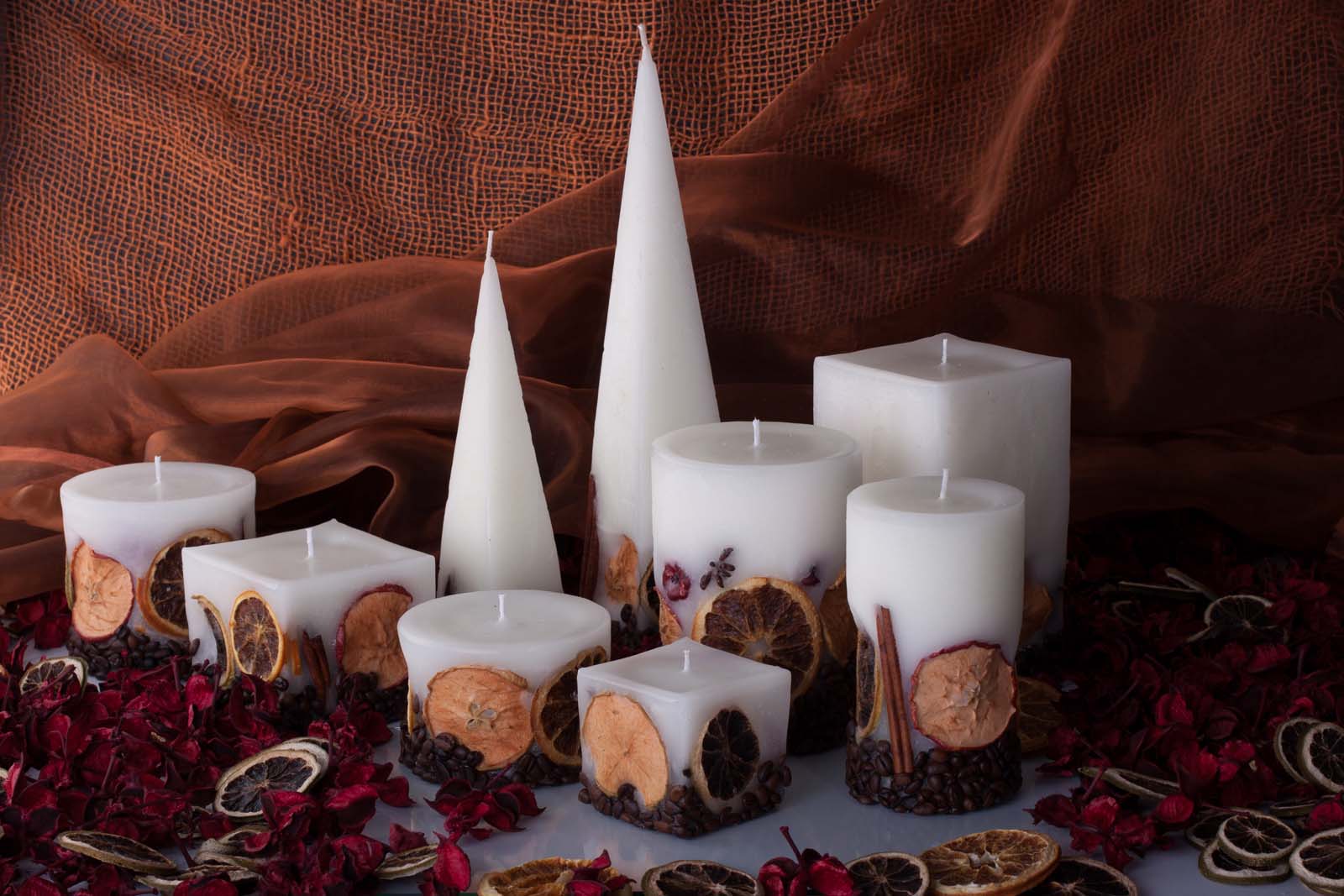 Nine white candles sitting on the table surrounded by the flower petals and dried orange slices