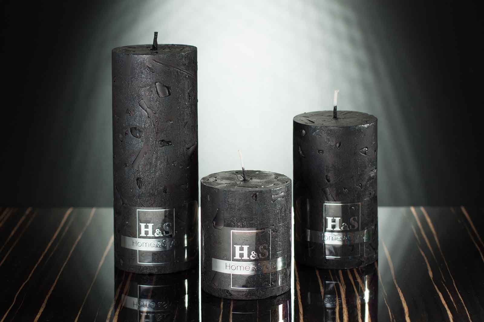Three black rustic pillar candles sitting on the black worktop with brown stripes
