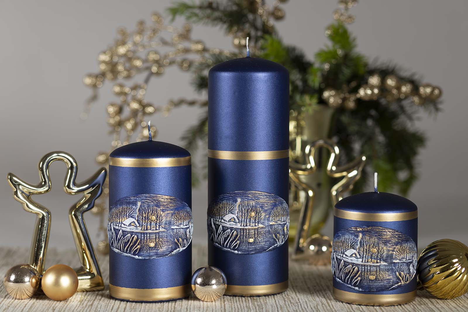 Three Pillar Christmas candles with Winter Lake ornament sitting beside two golden angels and Christmas bubbles 
