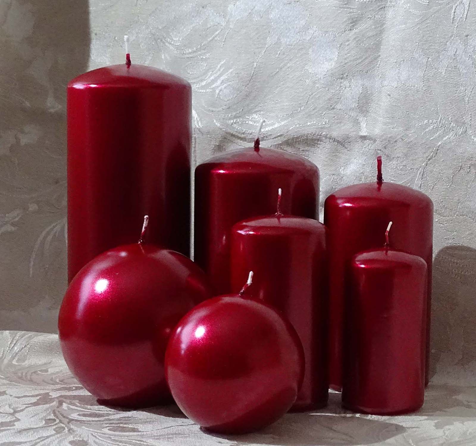 Five pillar and two round candles in metallic red colour sitting on the cream and silver cable cloth
