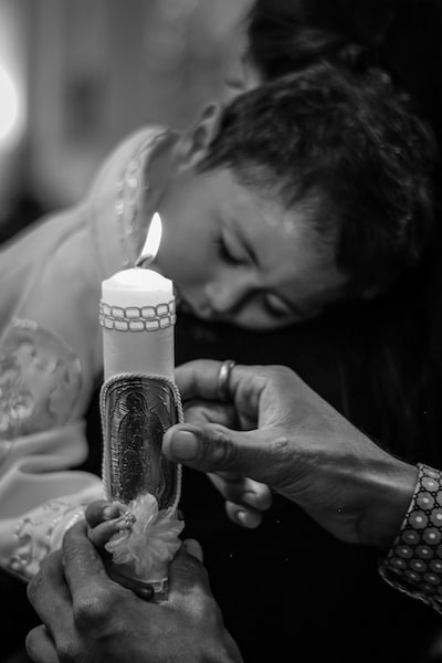 Mother is putting lighted candle into daughter’s hand