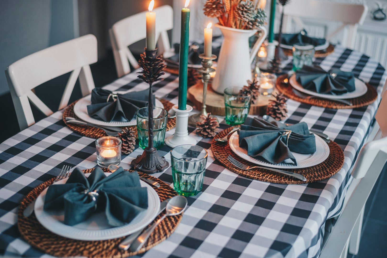 Dinning table with white plates, green glasses and tapper candles in the candle holders