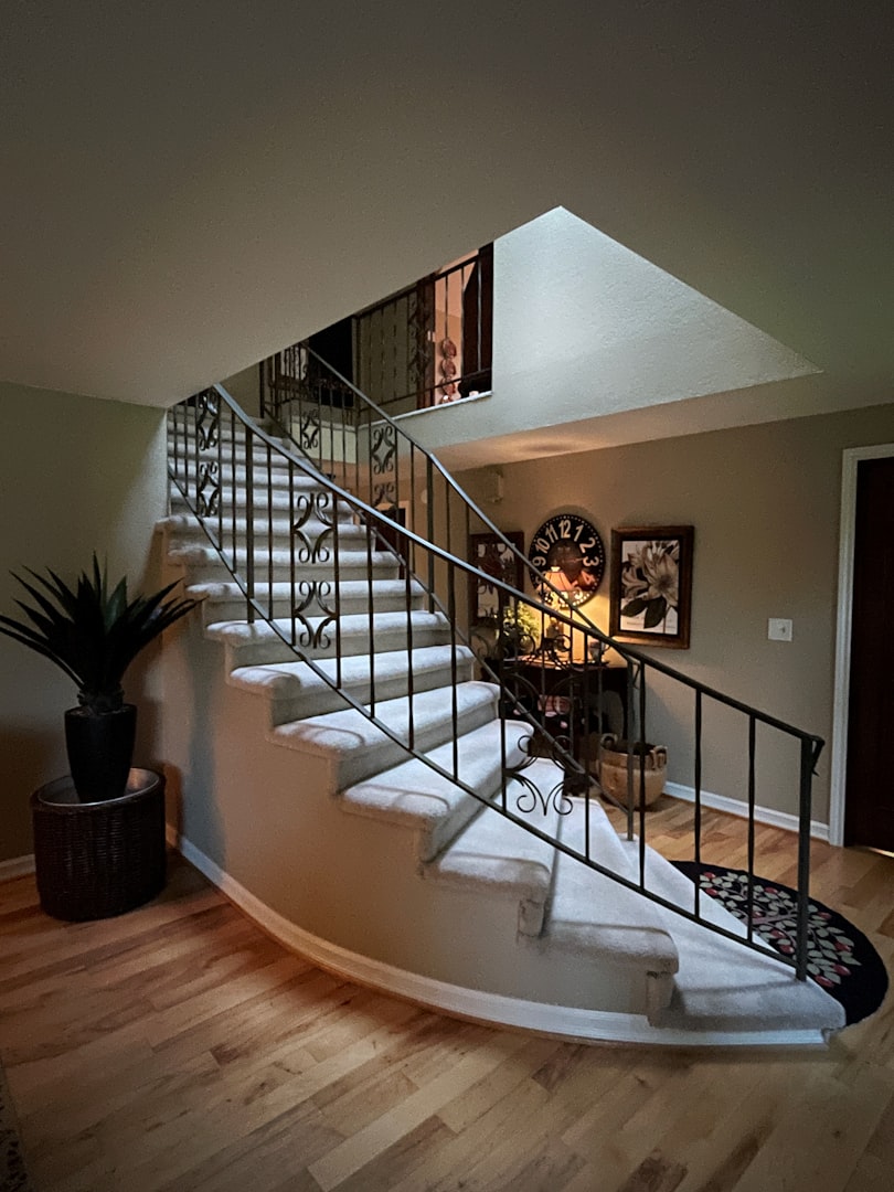 Hall with the staircase, black table with the lamp and two pictures and the clock