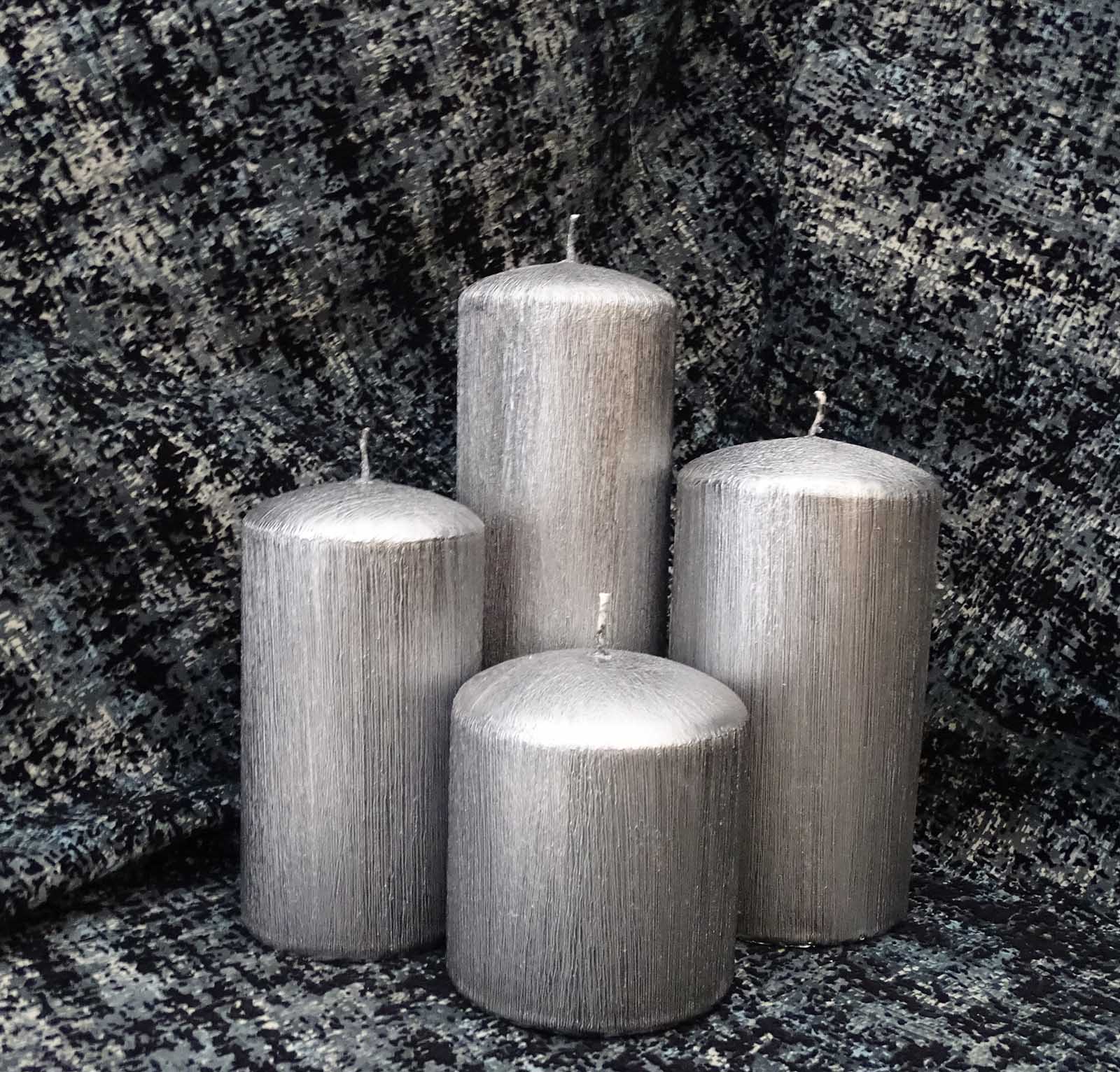 four brushed silver candles on the dark background